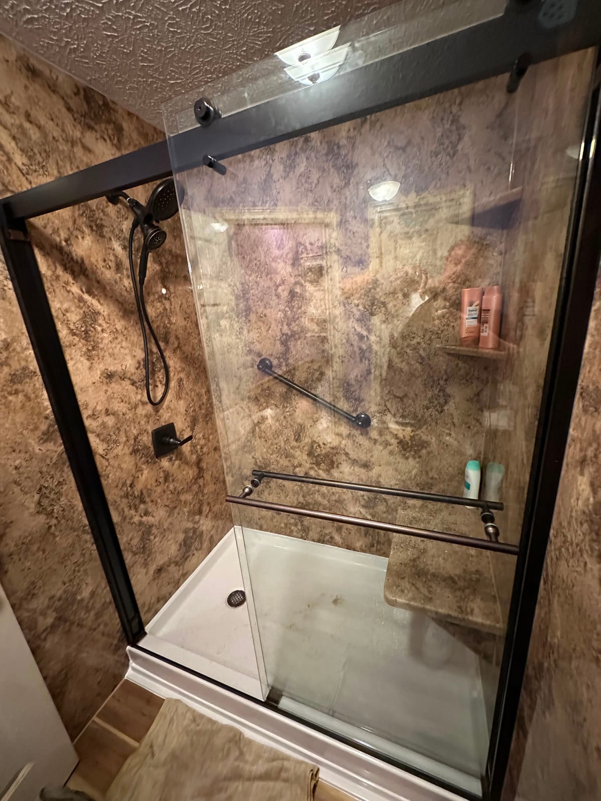 Walk-in shower with brown marble-look surround and sliding glass doors