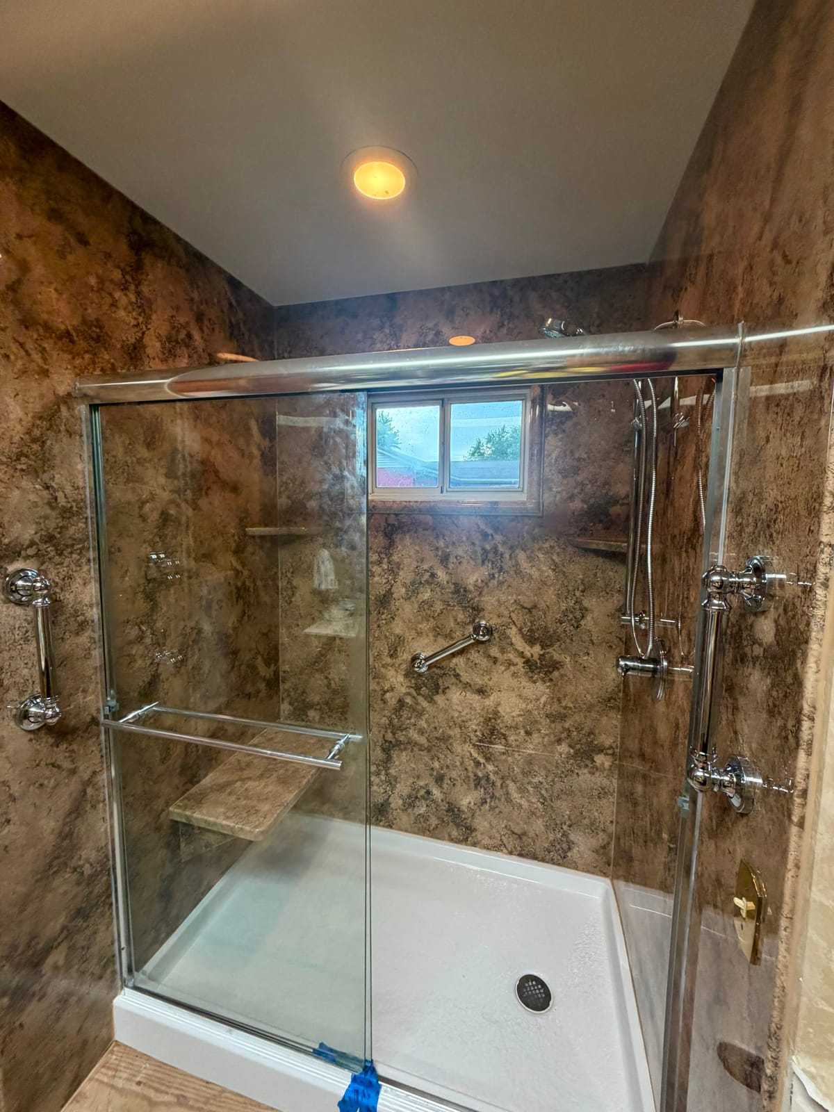 Walk-in shower with glass doors, corner bench and obscured window