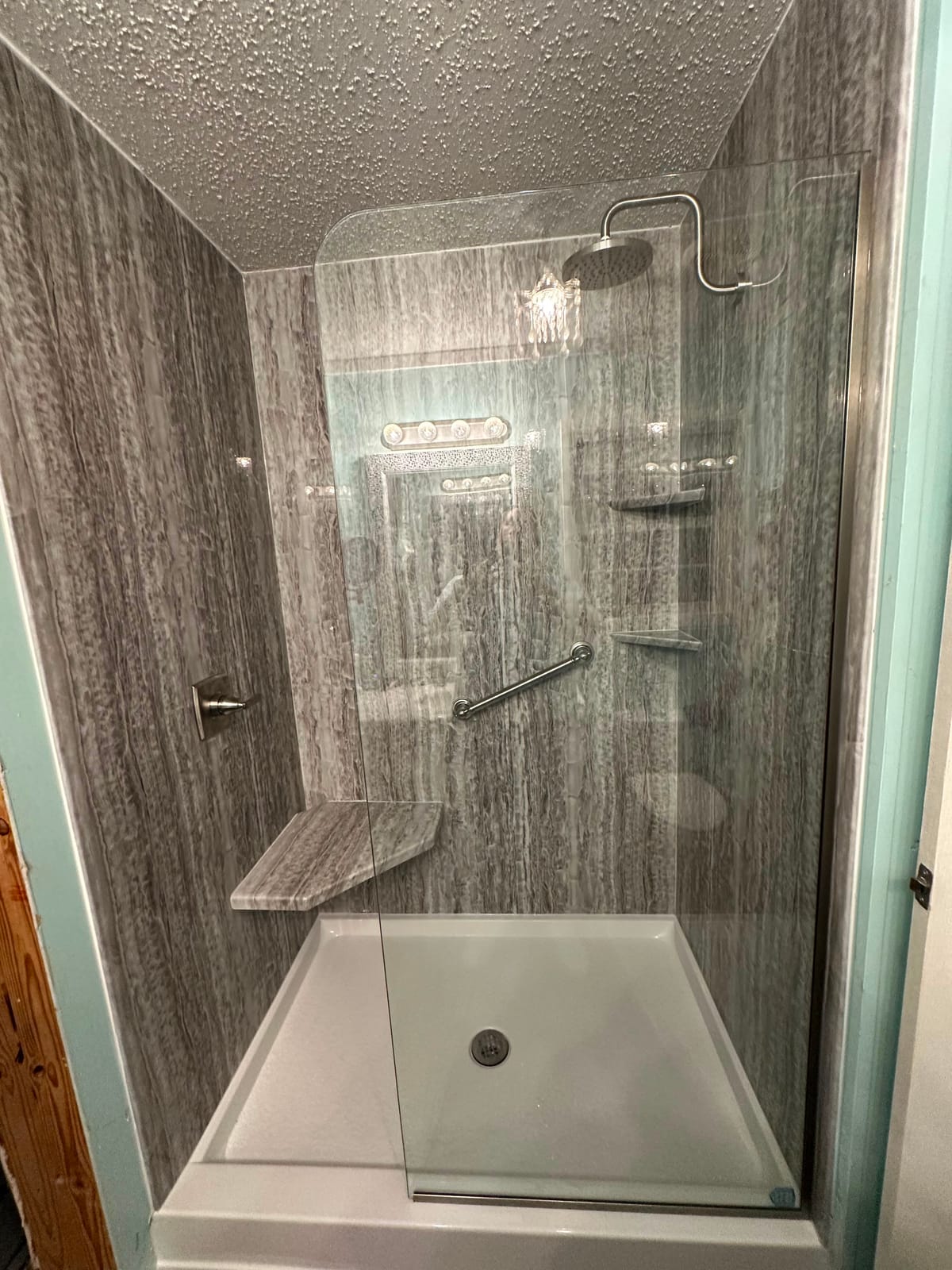 Walk-in shower with grey surround, rain shower head and corner shelves