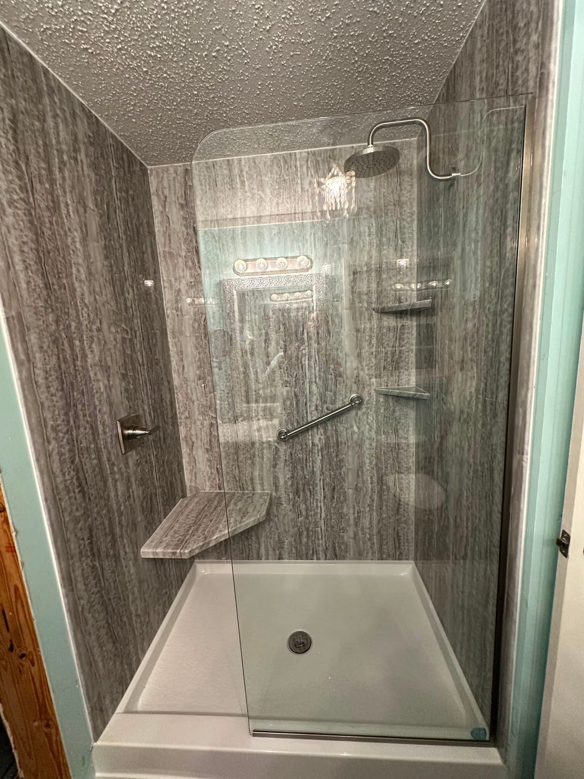 Walk-in shower with grey woodgrain-look surround and corner bench seat