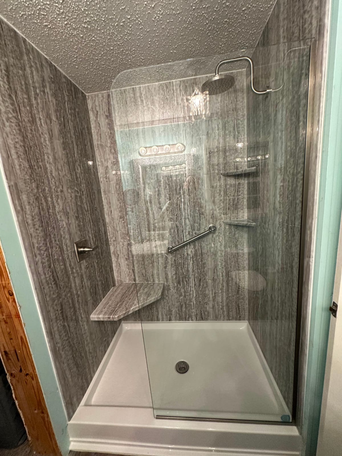 Walk-in shower with grey woodgrain-look walls and a fixed glass panel