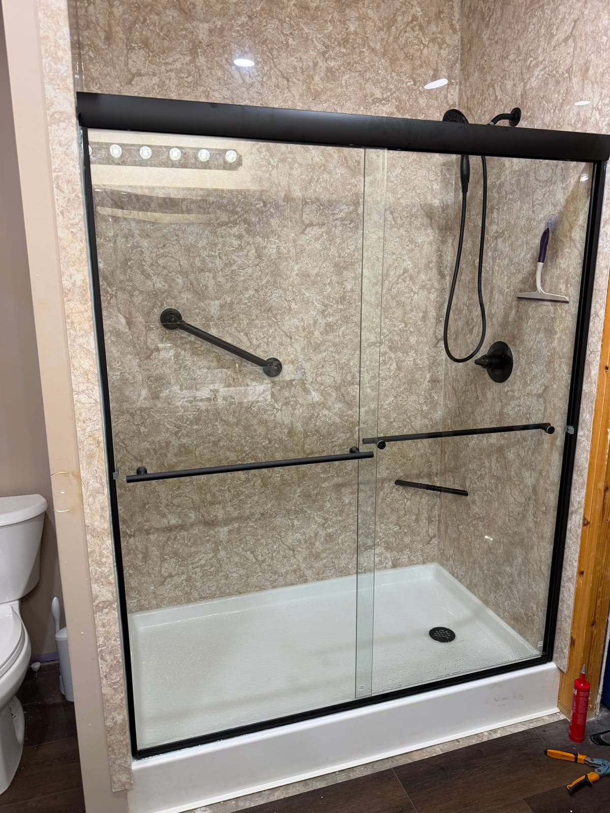 Walk-in shower with marble-look walls and frameless glass doors