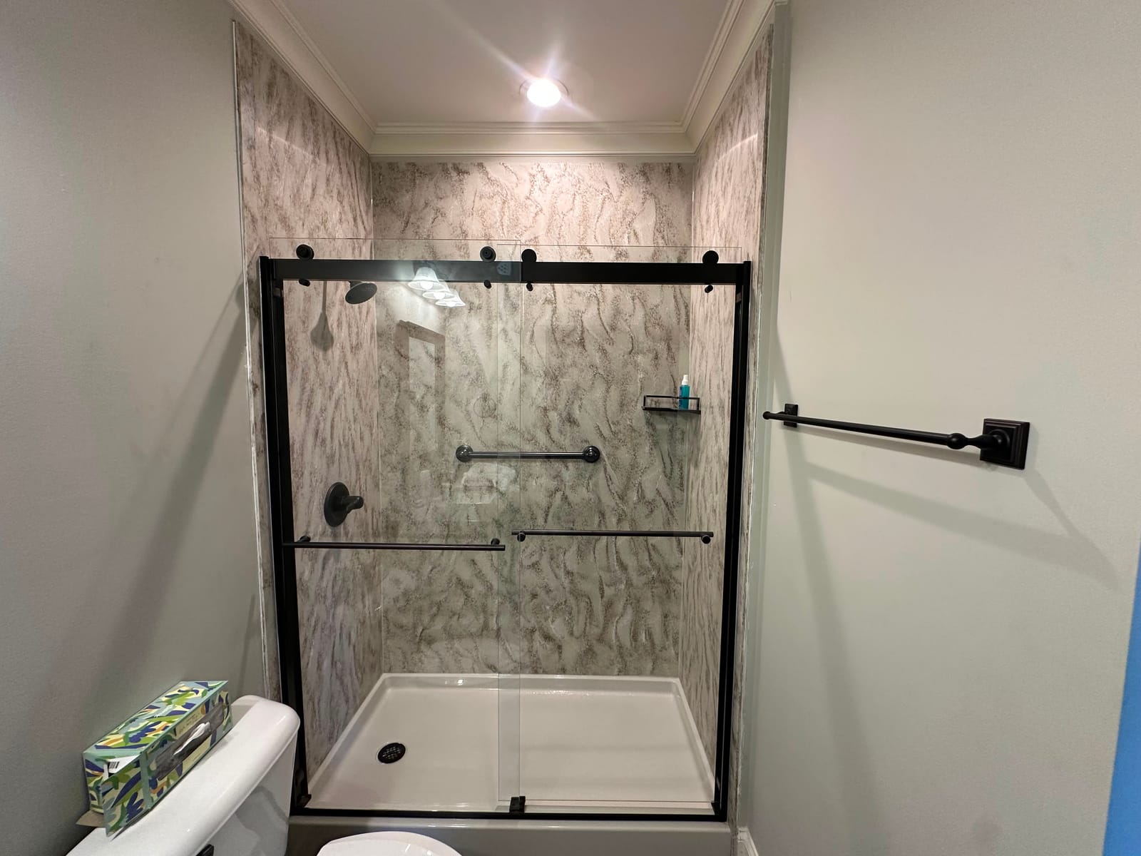 Walk-in shower with white marble-look surround and matte black hardware
