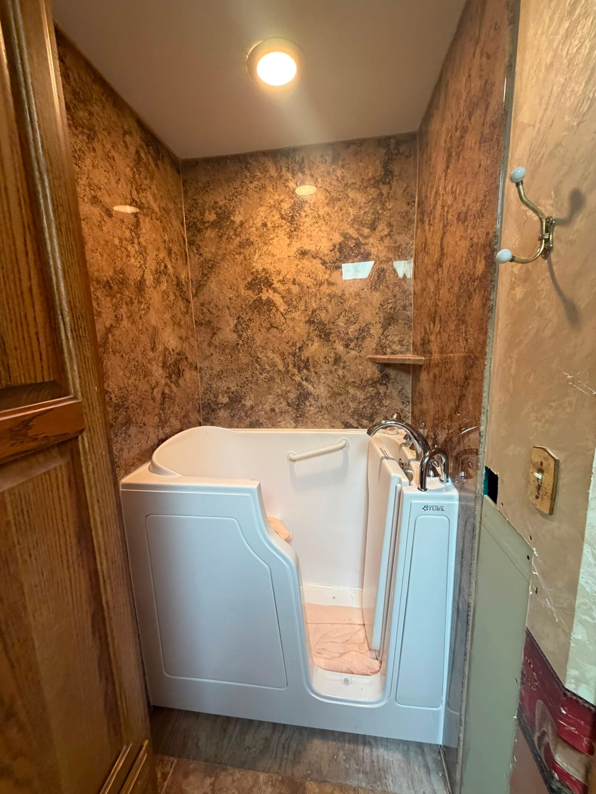 Walk-in tub installed with a brown marble-look surround