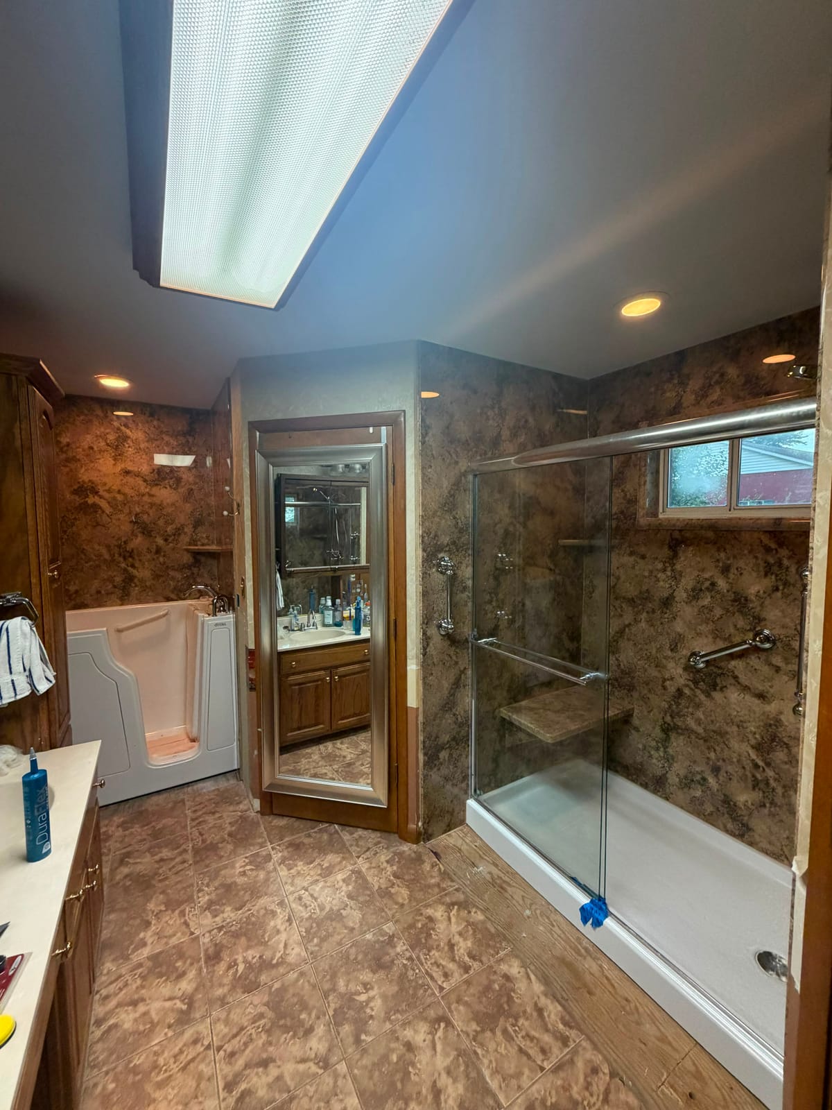 Bathroom with a walk-in tub and matching brown marble-look shower surround