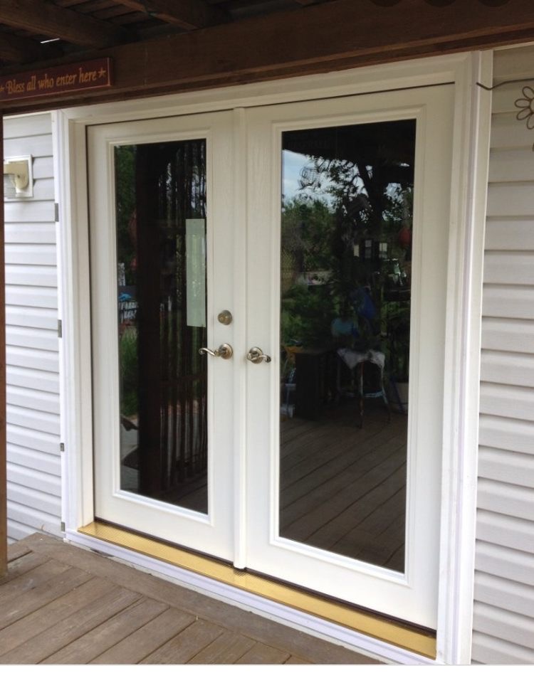 White double patio doors with full-length glass panels installed by Oakstone Kitchen and Bath, opening onto a wooden deck