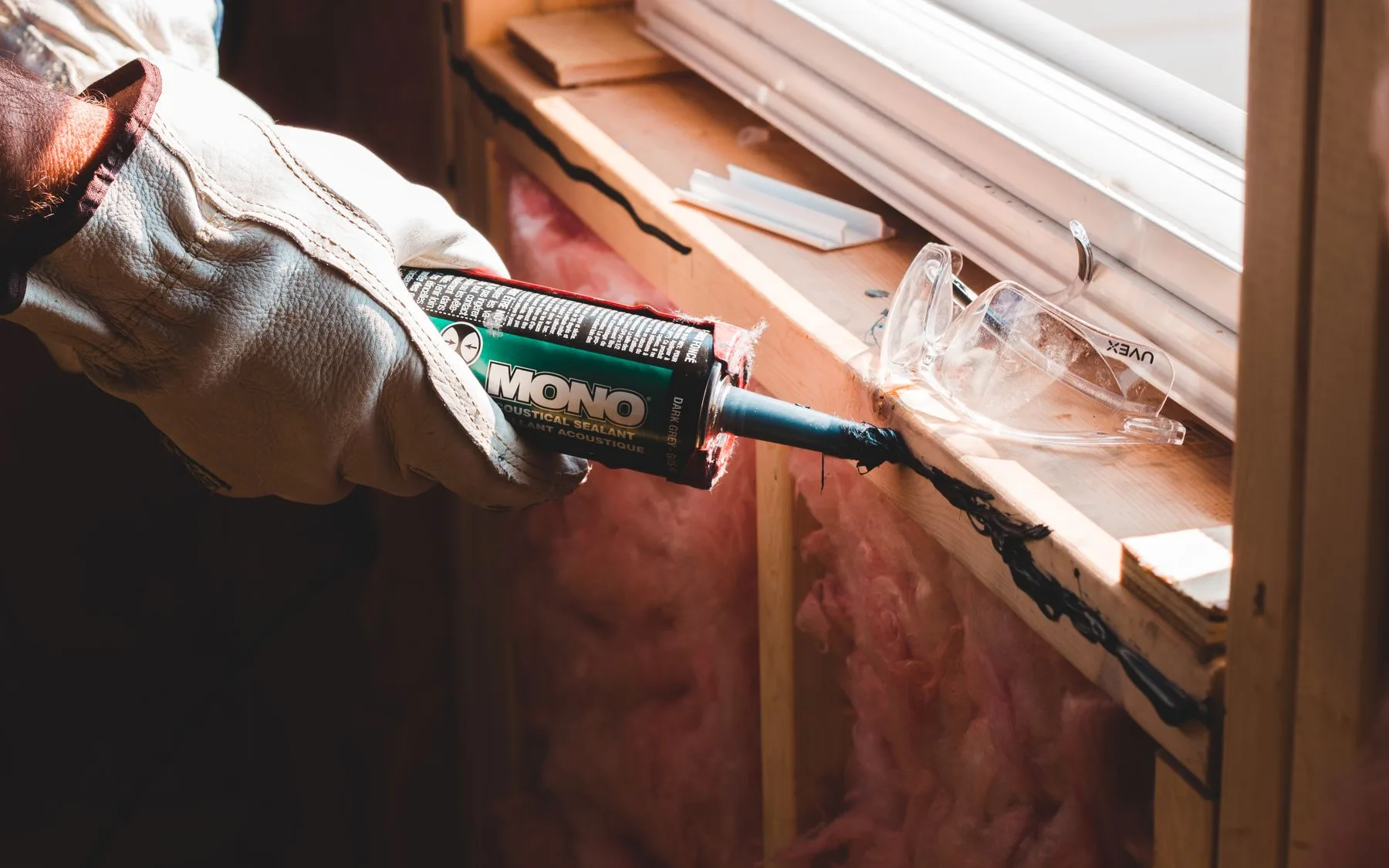 A gloved installer sealing a window sill during a replacement, shown for illustration